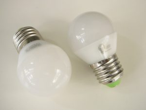 Dvě LED žárovky položené na bílém stole